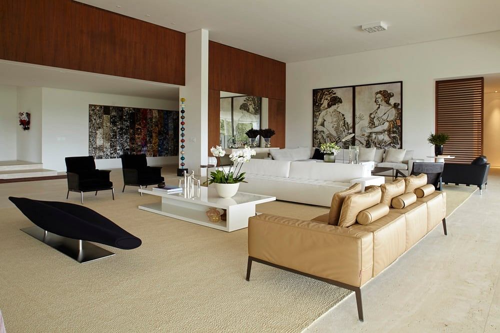 Spacious, modern living room with wooden panels, artwork, and neutral-toned furnishings.
