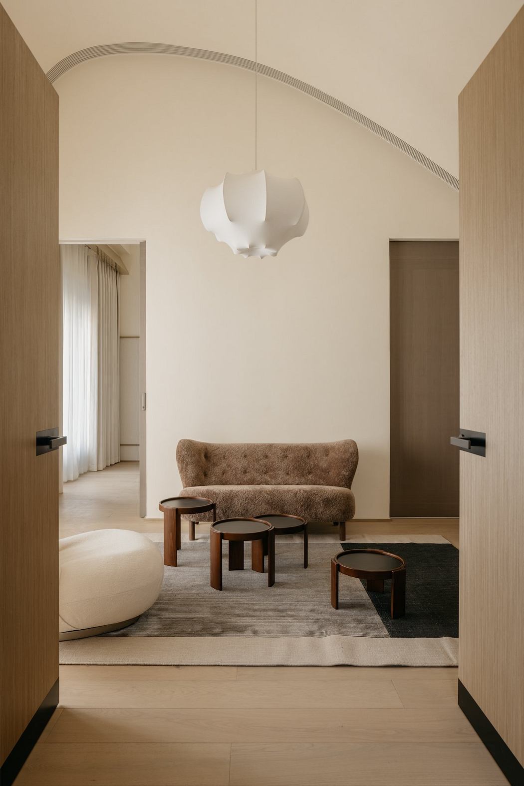 A cozy lounge area with a curved lighting fixture and wooden furniture pieces.