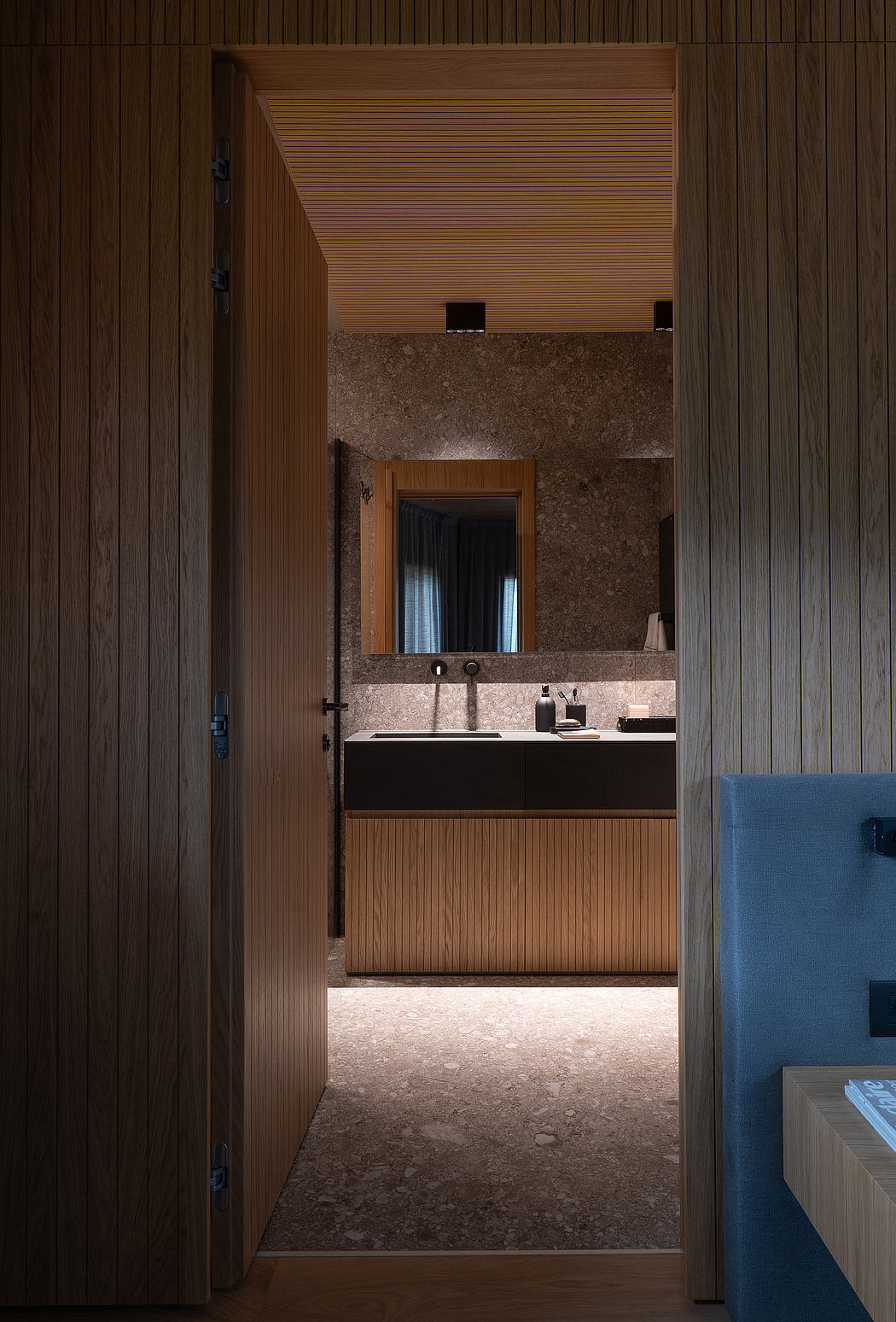 Wooden paneling, granite vanity, and recessed lighting in a minimalist bathroom.