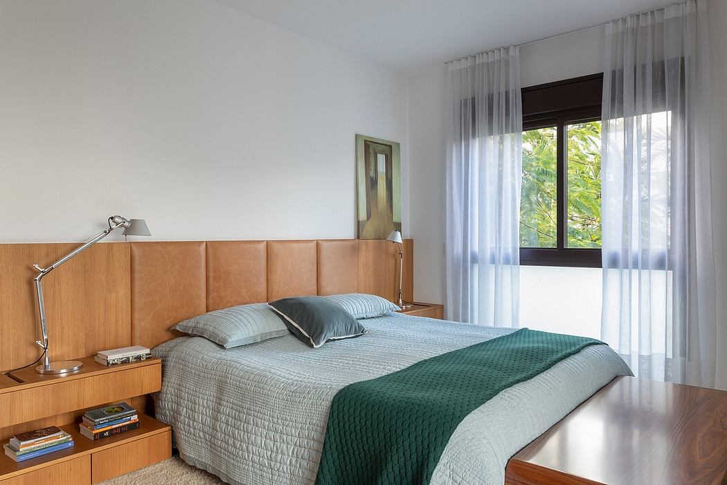 Cozy bedroom with wood furniture, large window, and soft curtains creating a tranquil ambiance.