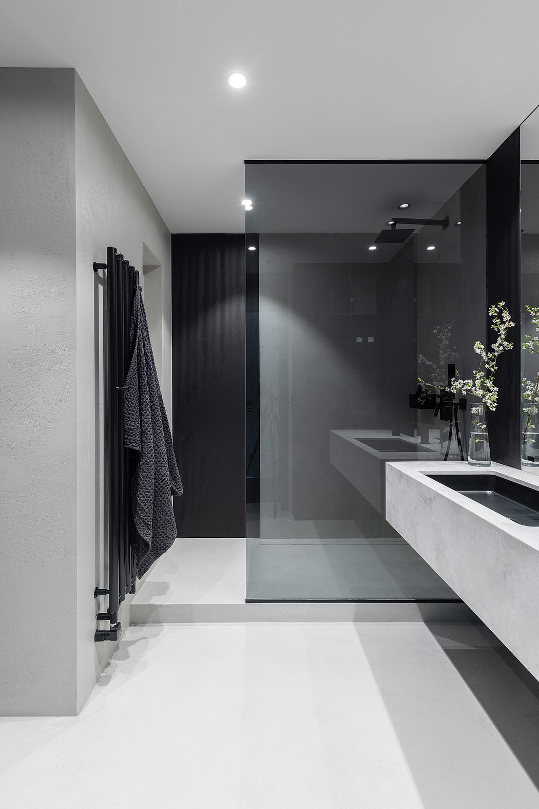 Sleek, minimalist bathroom with black and white tones, recessed lighting, and a marble vanity.