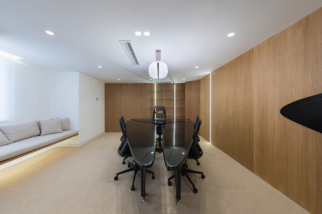 A modern, minimalist workspace with a sleek glass table, wooden walls, and recessed lighting.