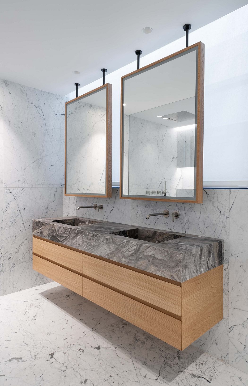 Minimalist bathroom with wooden vanity, marble countertop, and wood-framed mirrors.
