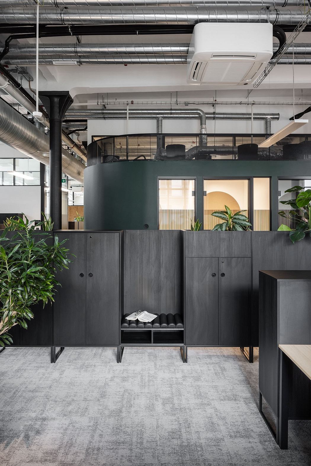Sleek, industrial-style office space with modern furniture, open layout, and lush greenery.