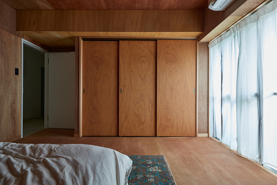 Spacious bedroom with wooden walls, sliding closet doors, and a patterned area rug.