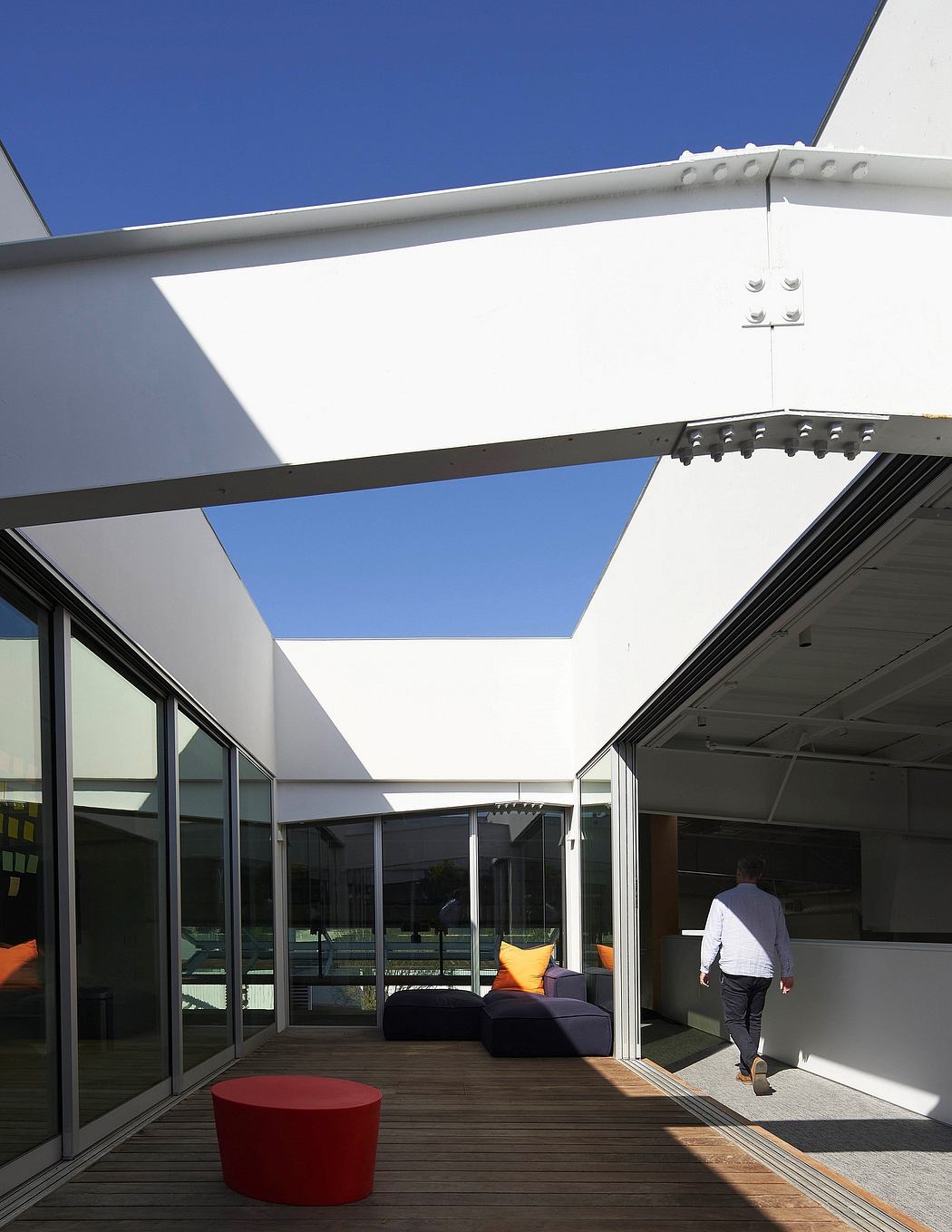 Modern architectural design with white roofline, glass walls, and comfortable patio seating.