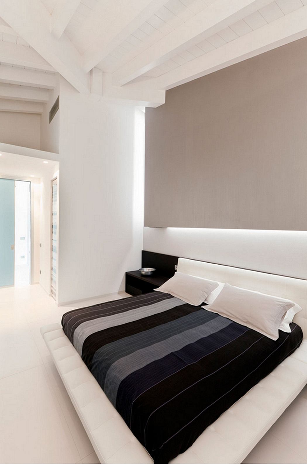Minimalist bedroom design with recessed lighting, striped bedding, and neutral color palette.