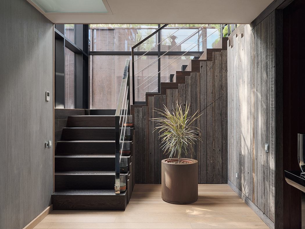 A modern, minimal staircase design with glass panels and a potted plant accent.