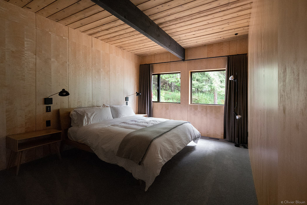 A cozy, rustic bedroom with wooden beams, large windows, and a minimalist design.