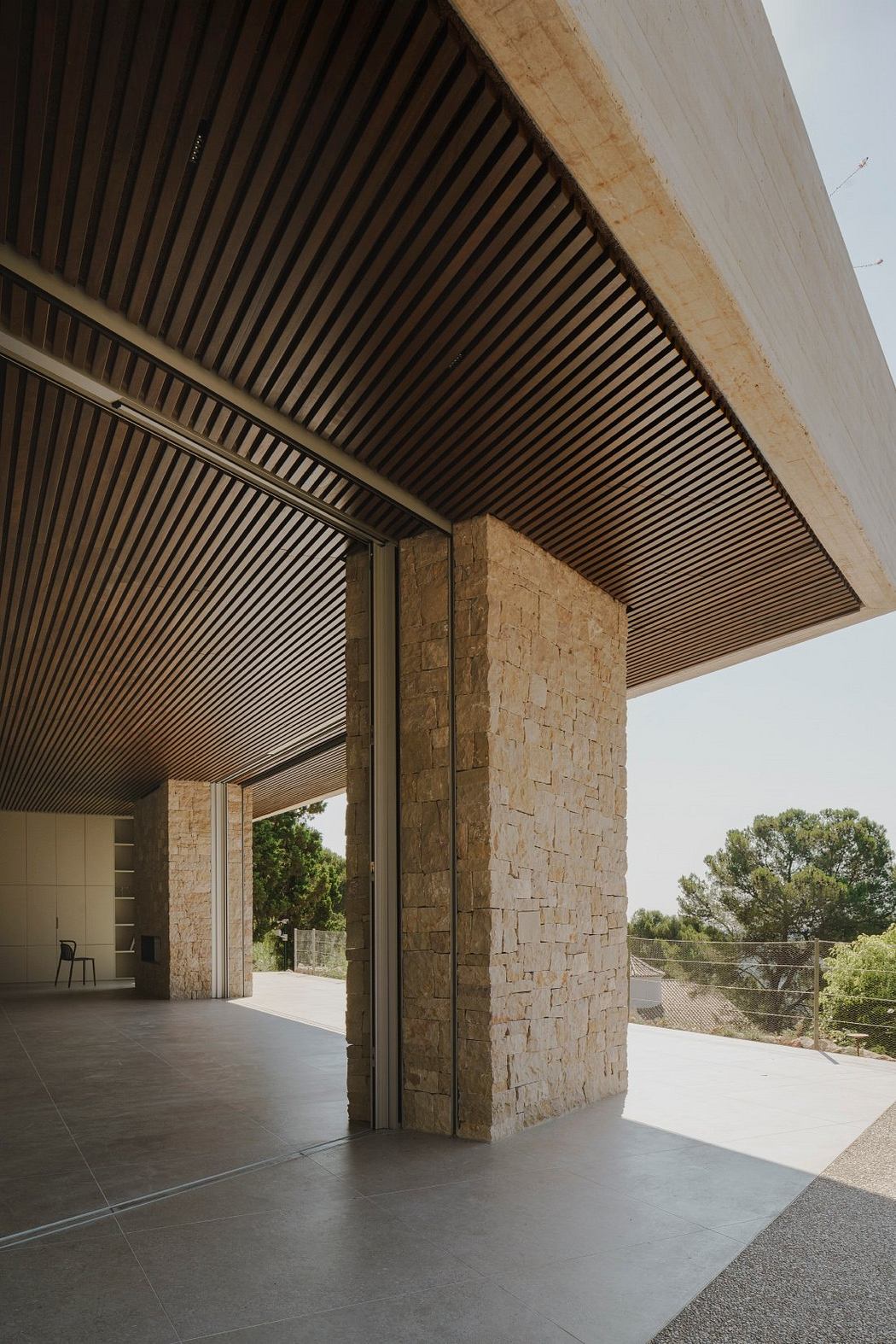 Dramatic vaulted wooden ceiling and stone columns frame an expansive outdoor view.
