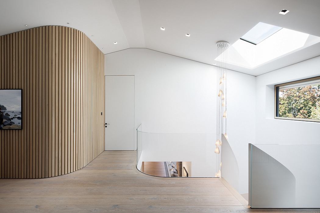 Modern open-plan interior with arched wooden wall paneling, skylight, and minimalist stairs.