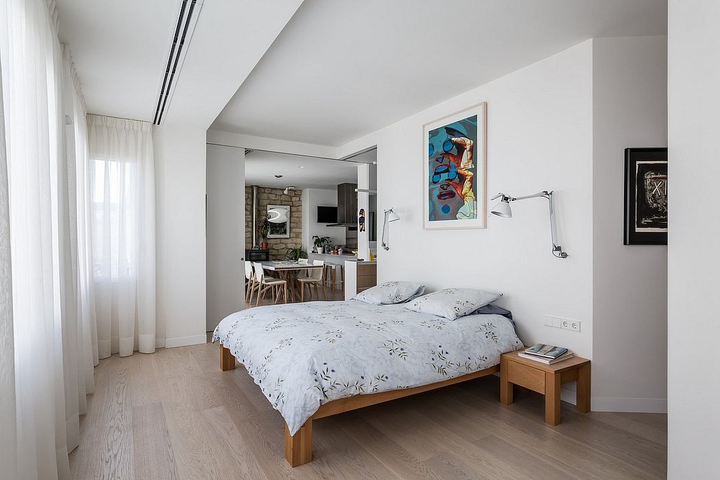 Spacious bedroom with minimalist furnishings, hardwood floors, and modern artwork.