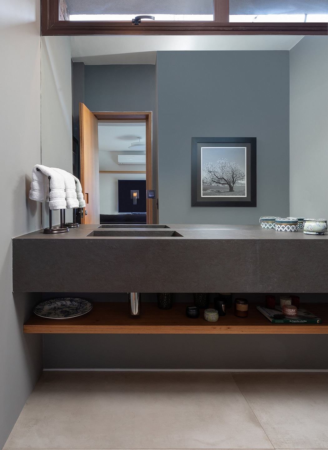 Serene bathroom with dark vanity, framed artwork, and wooden shelves.