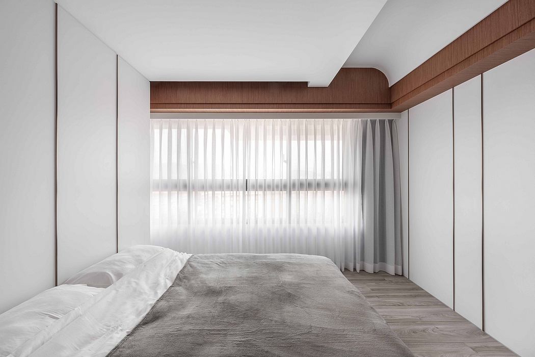 Minimalist bedroom with wooden accent wall, built-in shelving, and large window providing natural light.