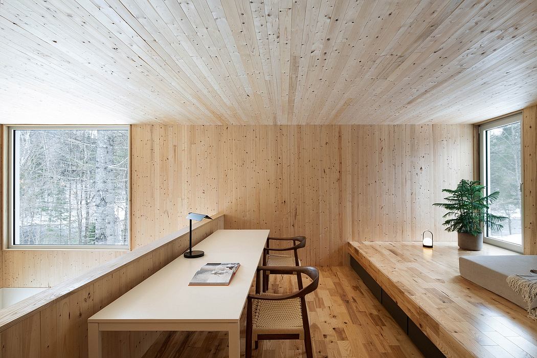 Cozy wooden interior with minimalist design and large windows overlooking nature.