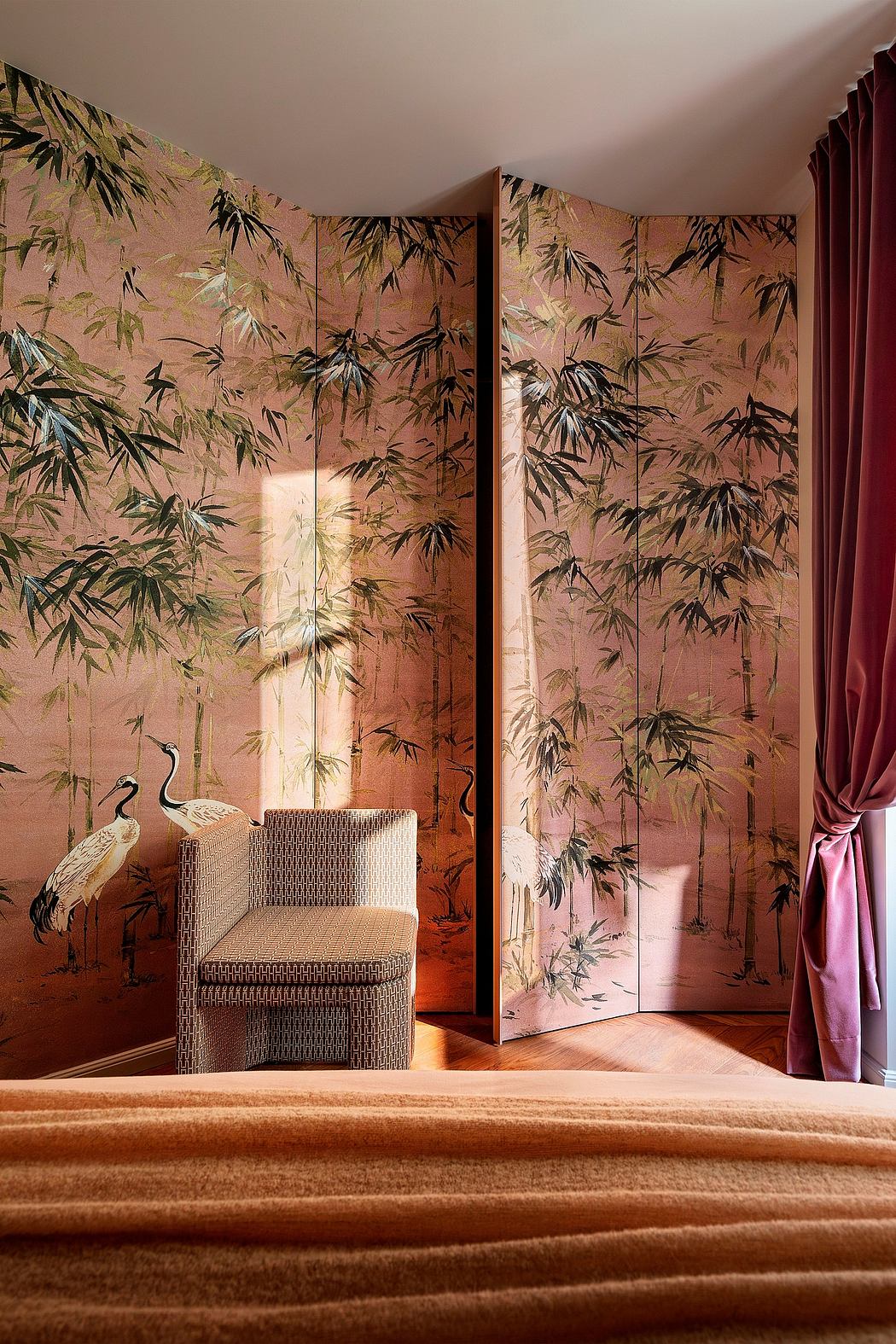 Elegant room with bamboo-patterned walls, wicker chair, and luxurious burgundy curtains.