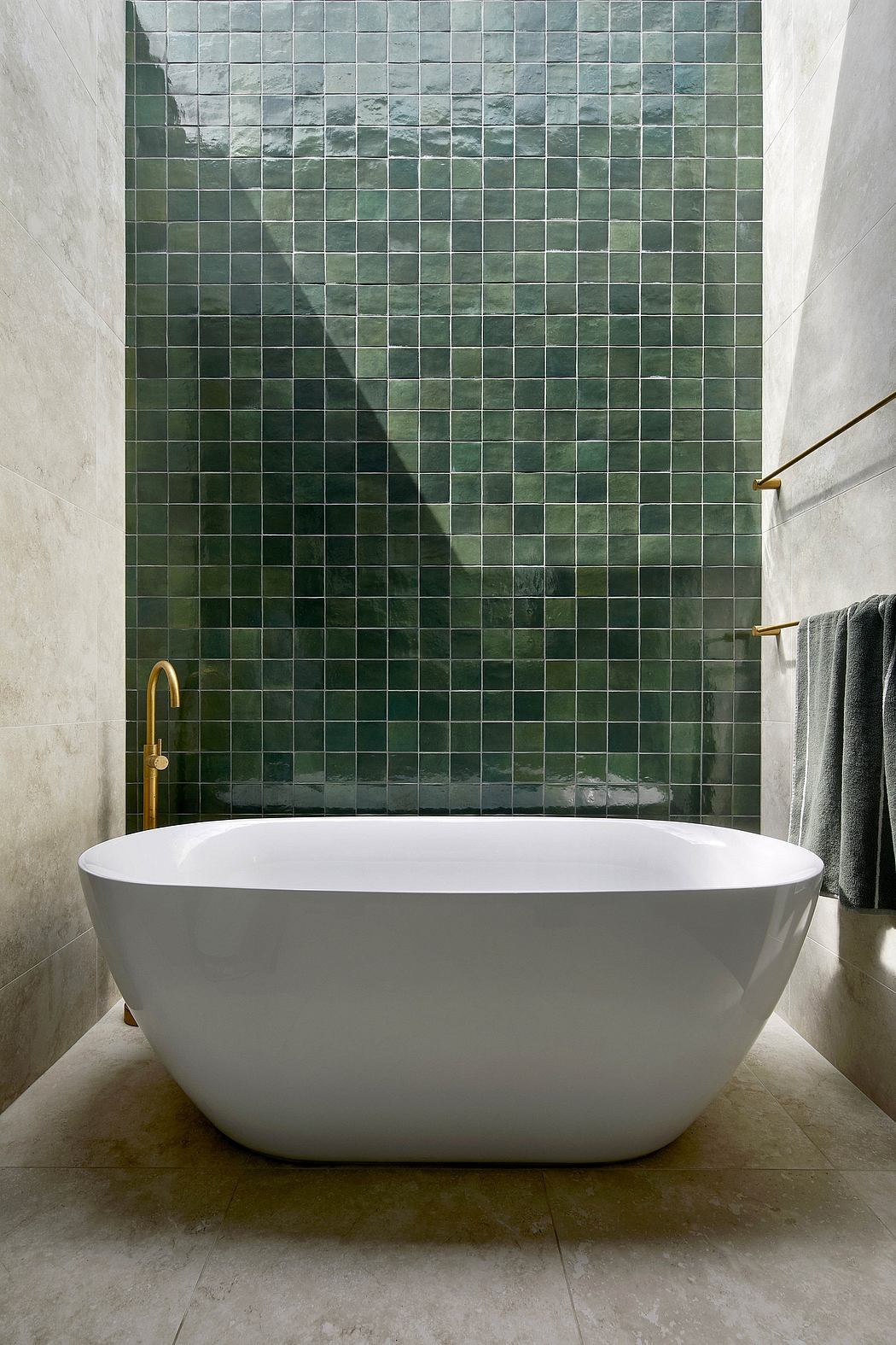 A modern bathroom with a freestanding white tub and a striking green tile wall.