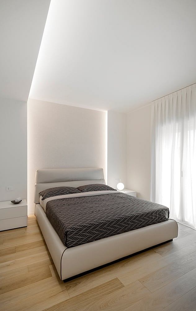 Minimalist bedroom design with white walls, wooden floors, and a modern platform bed.