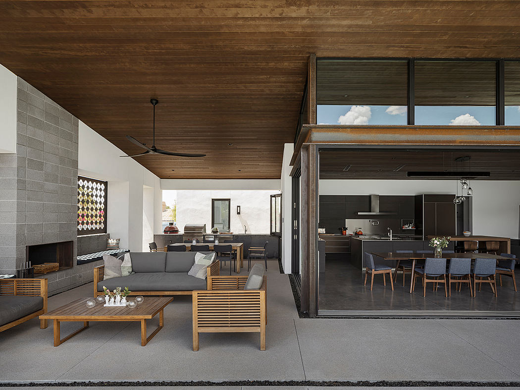 A spacious open-concept living area with wooden ceiling, modern furniture, and large windows.