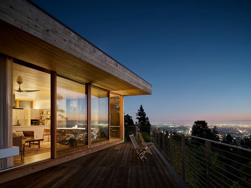 Cozy wooden cabin with large glass windows overlooking a cityscape at dusk.