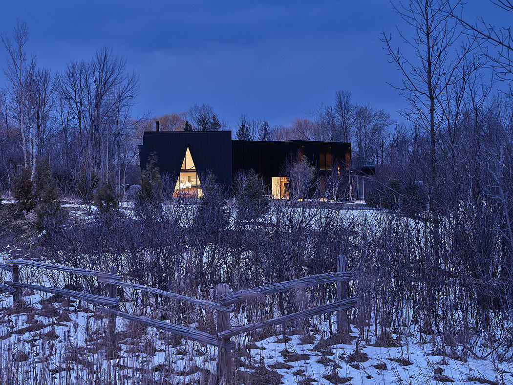 Modern, geometric cabin nestled in a snowy forest, warm lights glowing through its angular windows.