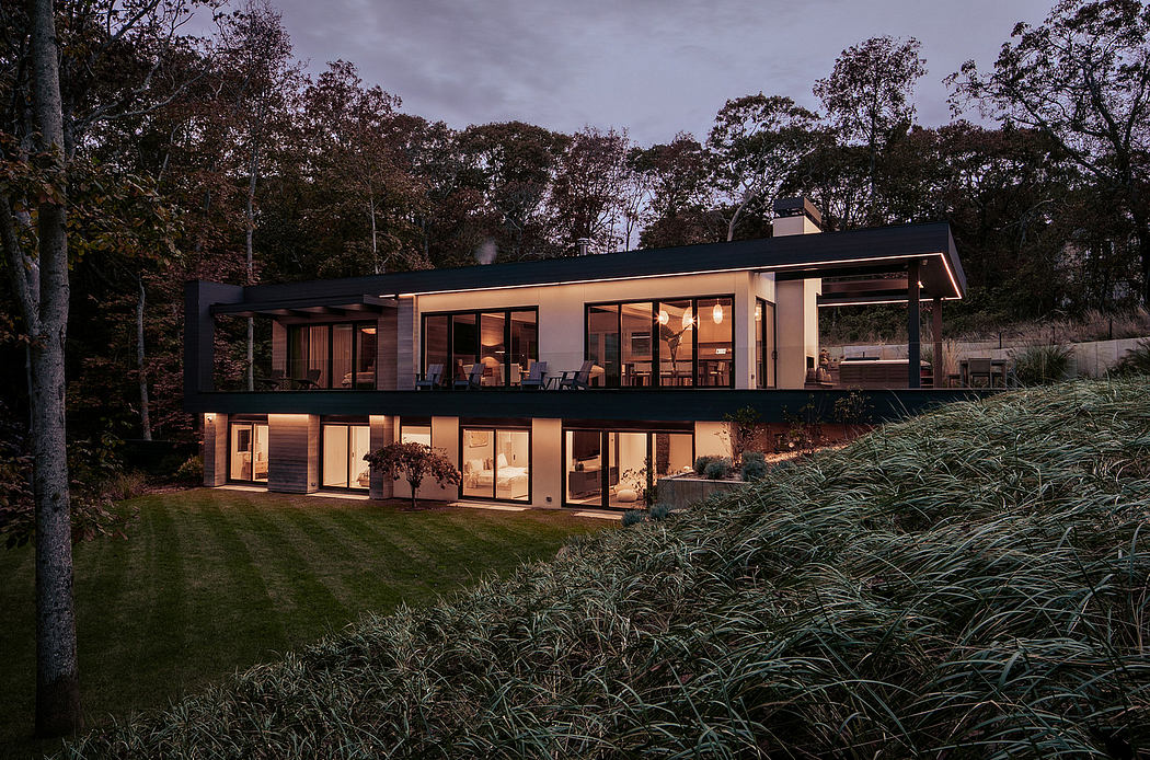 Stylish, modern two-story lakeside home with expansive windows and deck overlooking lush landscape.