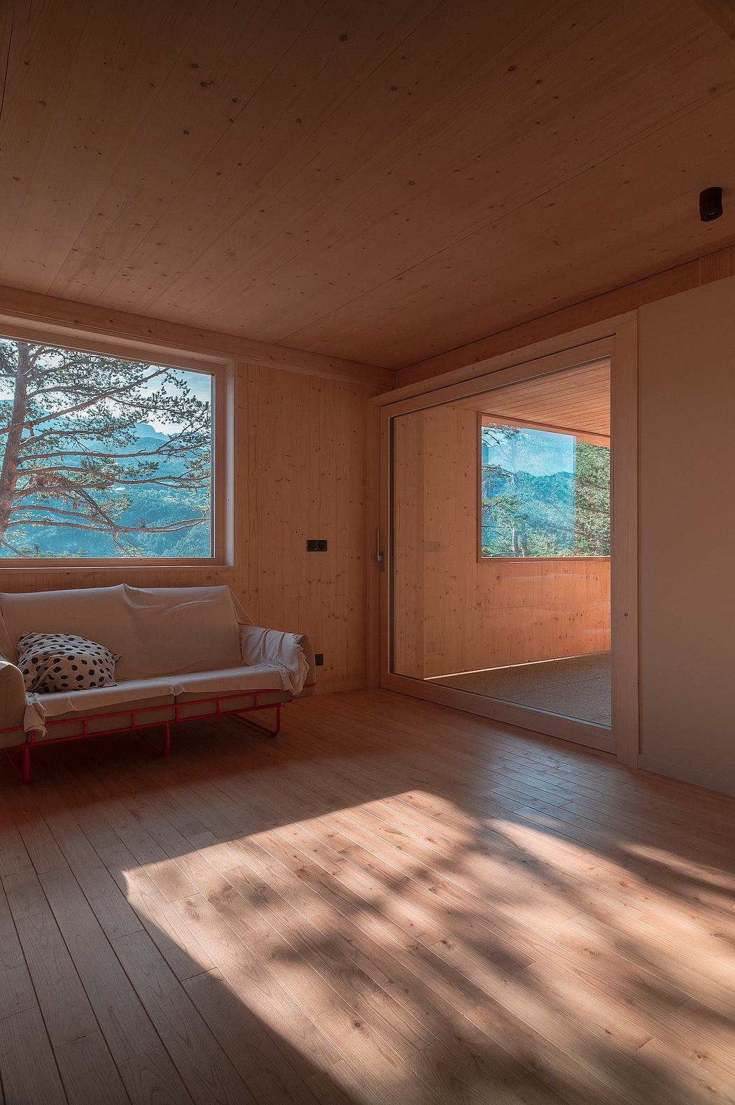 A cozy, wood-paneled room with large windows framing a scenic mountain view and a comfortable sofa.