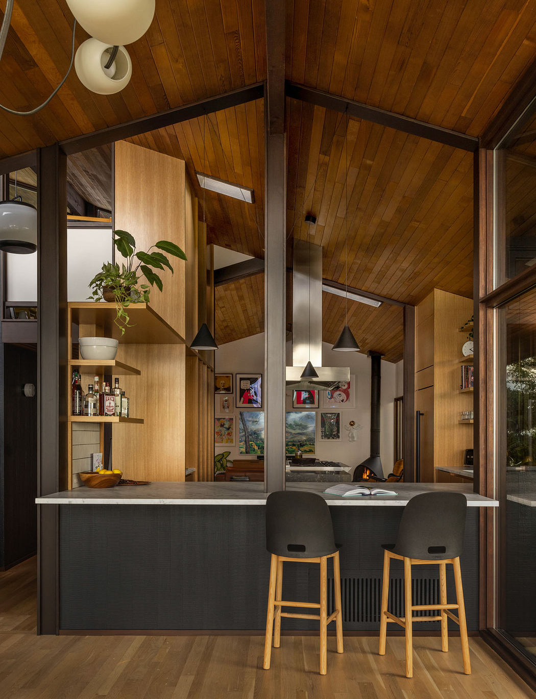 A cozy wooden cabin interior with a sleek kitchen counter, pendant lights, and artistic decor.