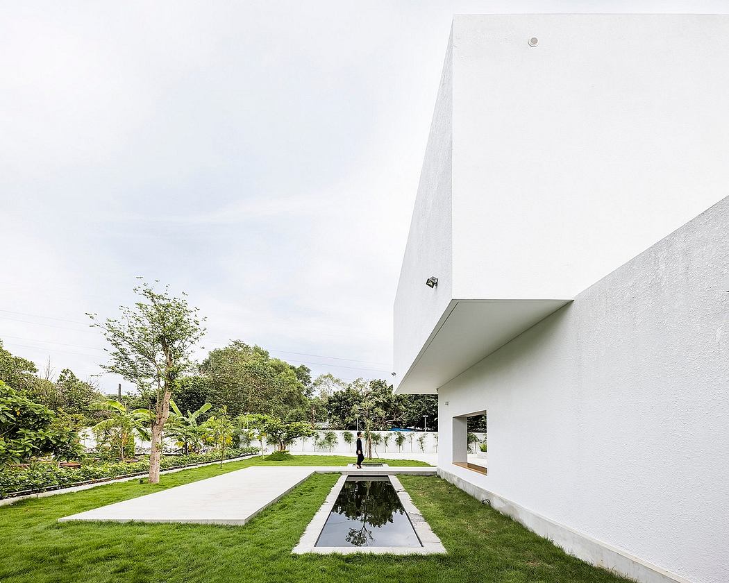 Striking minimalist architecture with a reflecting pool and lush greenery surrounding.