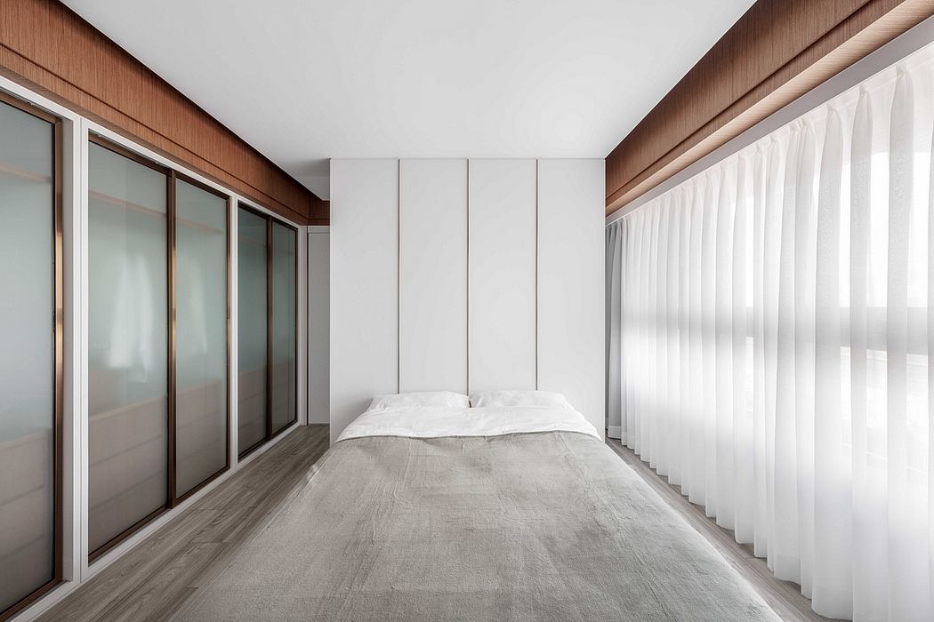 Minimalist bedroom with wood paneled walls, sliding glass doors, and sheer white curtains.