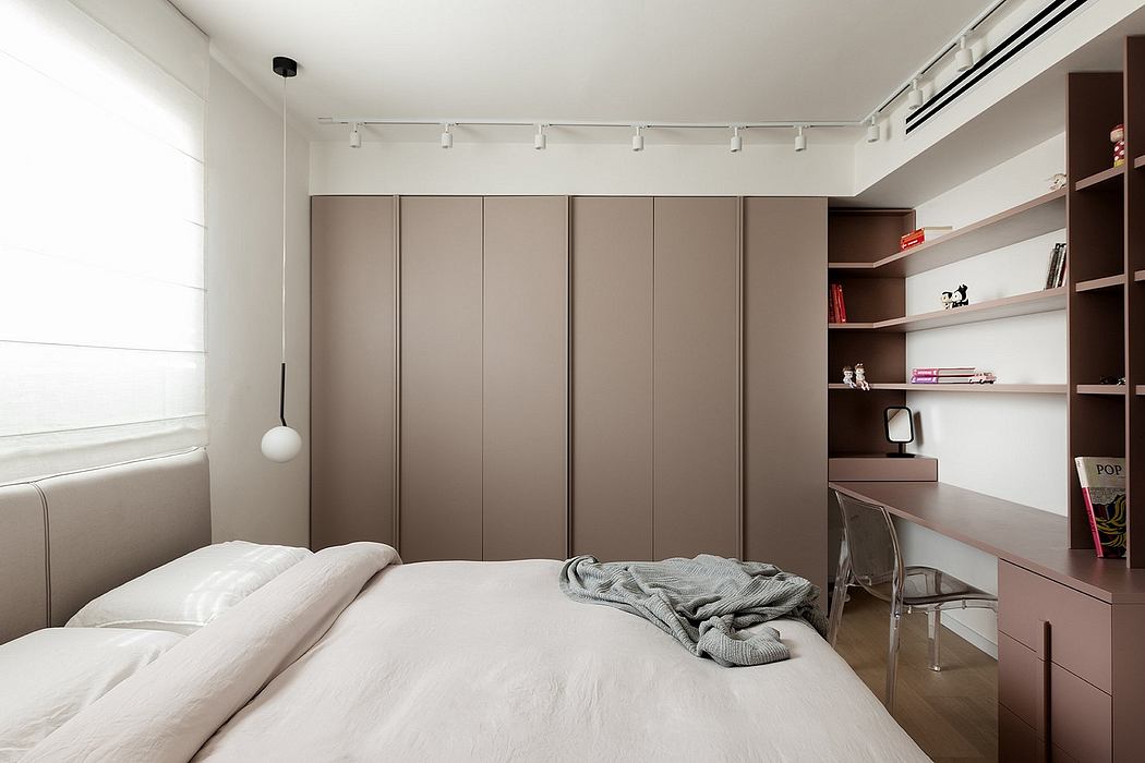 Minimalist bedroom with built-in wardrobe, desk, and shelving system showcasing clean lines and neutral tones.