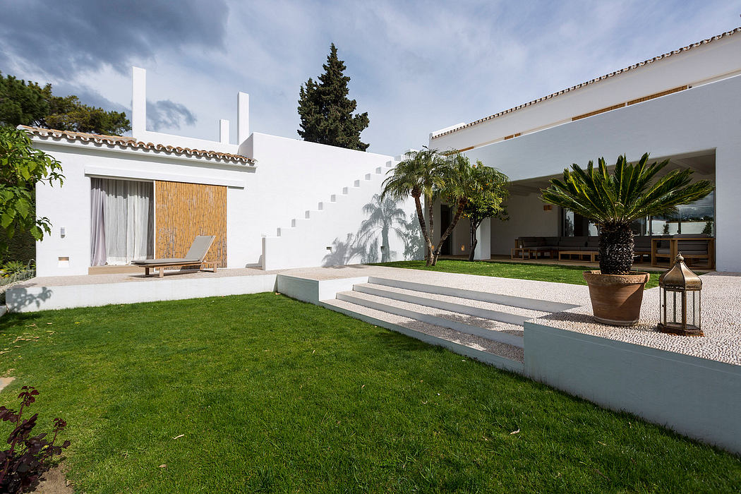 Modern Mediterranean-style villa with clean lines, lush greenery, and outdoor seating area.