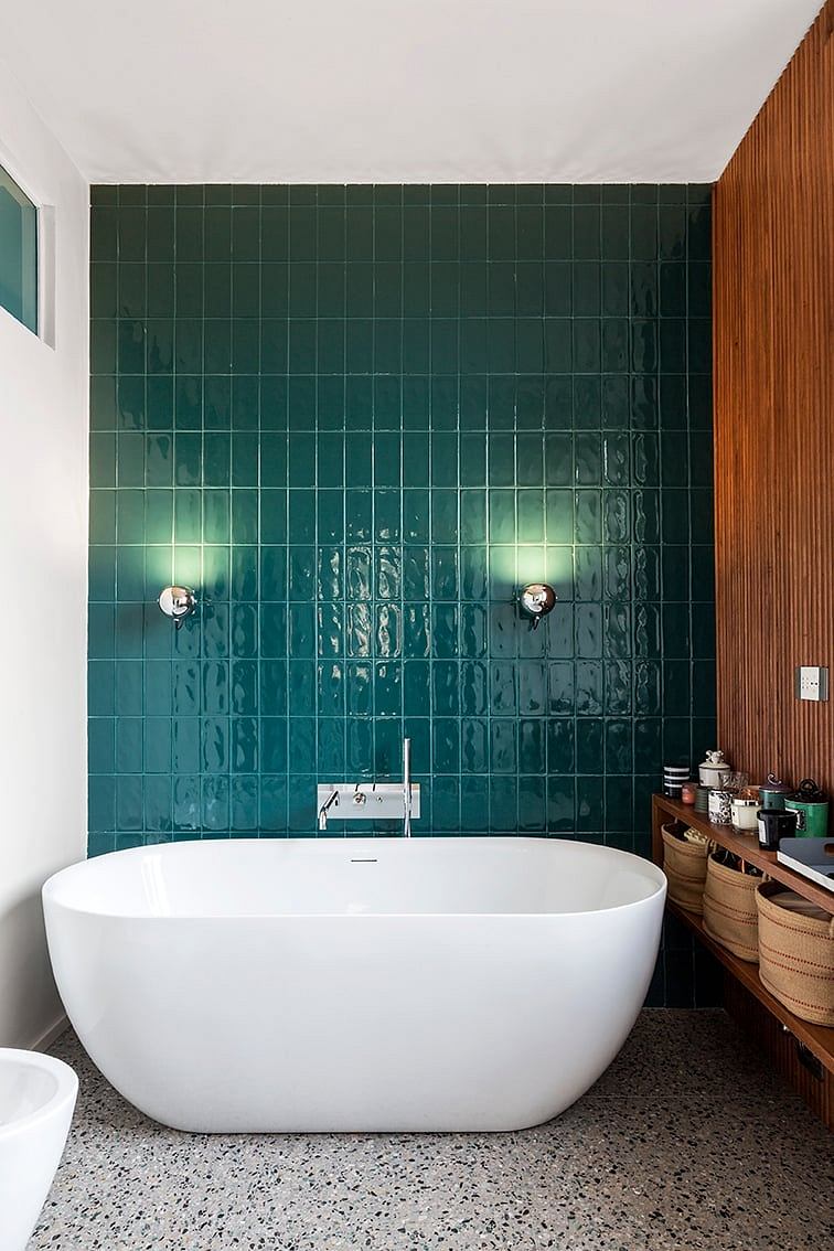 Sleek, modern bathroom with a freestanding white tub and green tile wall.