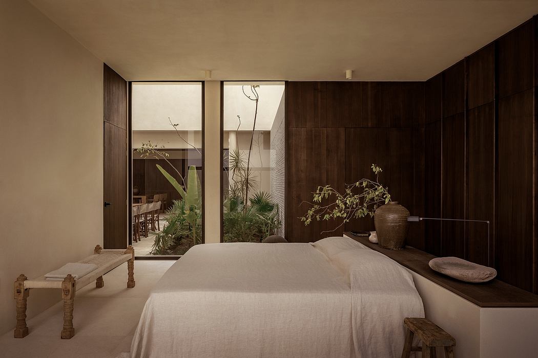 A cozy, earthy bedroom with large windows, wood paneling, and potted plants.