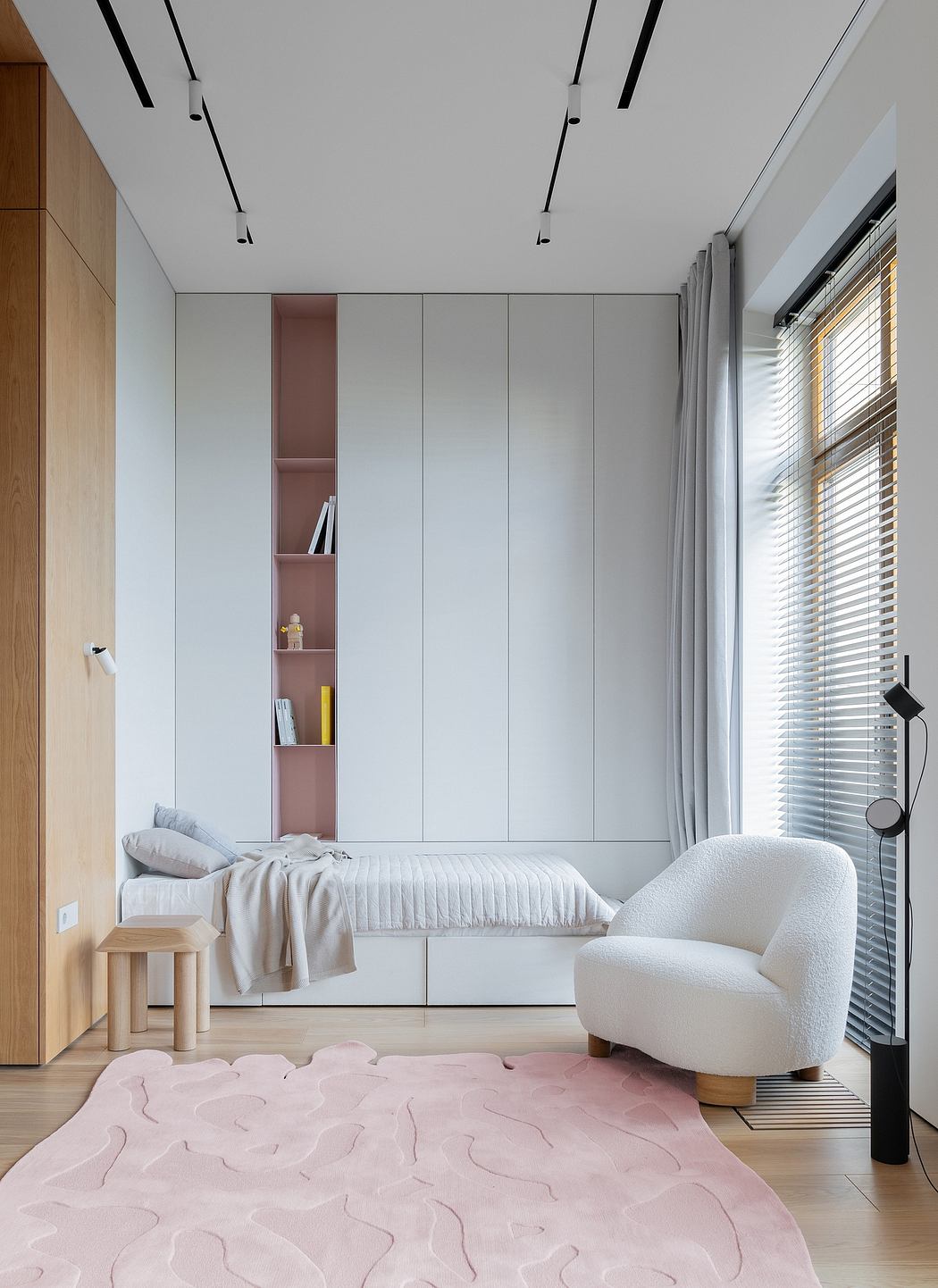 Minimalist bedroom with built-in cabinetry, plush upholstered chair, and abstract rug.