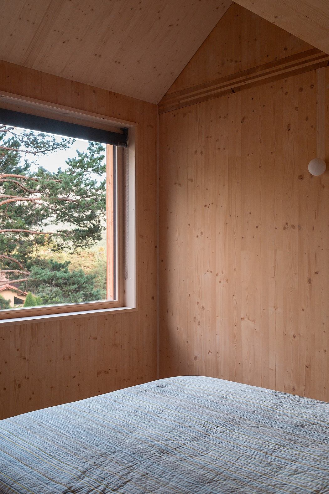 A cozy wood-paneled bedroom with a large window overlooking lush greenery.