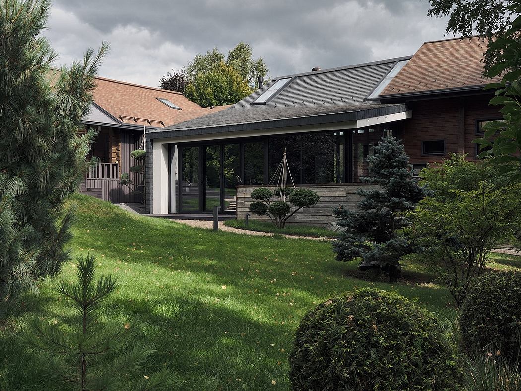Rustic wooden lodge surrounded by lush greenery and pine trees, with large glass windows.