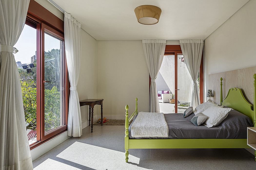 Cozy bedroom with large windows, vibrant green bed frame, and wood-framed furniture.