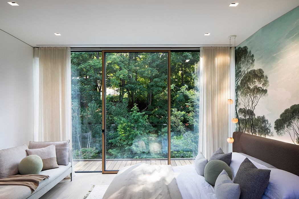 Large windows offer scenic views of the lush, forested surroundings in this cozy bedroom.