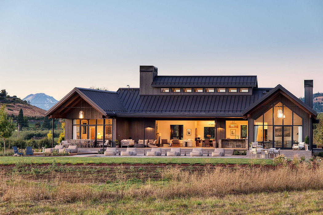 A modern, rustic lodge with a large wraparound porch and panoramic mountain views.