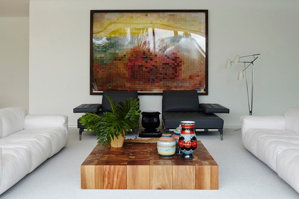 Vibrant abstract mosaic artwork frames plush seating and wooden coffee table in modern decor.