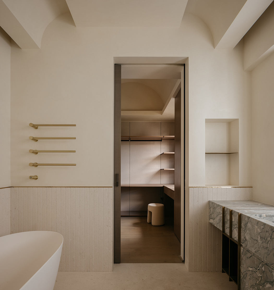 A minimalist bathroom with a closet, marble countertop, and brass fixtures.