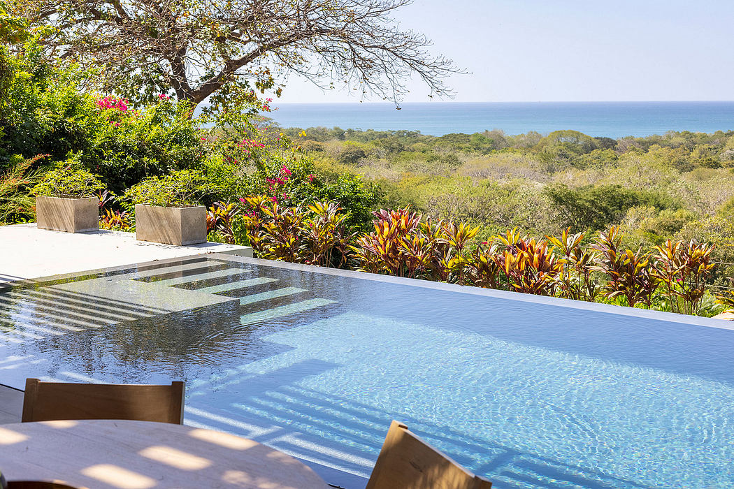 Stunning infinity pool overlooking lush tropical foliage and the ocean beyond.