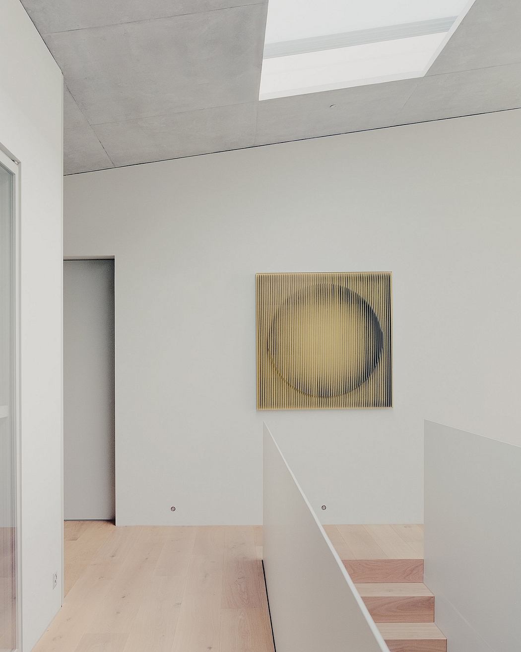 Modern minimalist interior with concrete ceiling, wood floors, and abstract wall art.