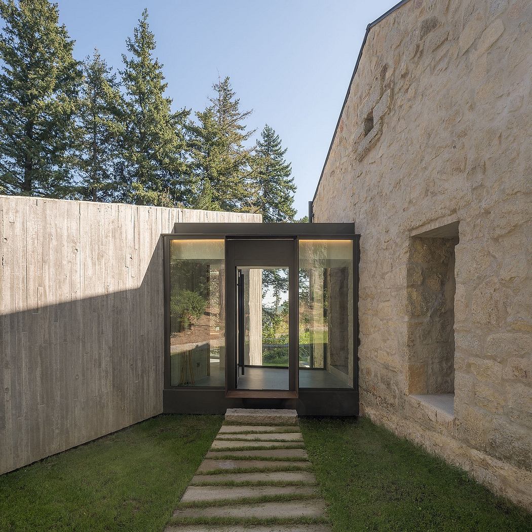 Rustic stone exterior with modern glass entryway, illuminated by recessed lighting.
