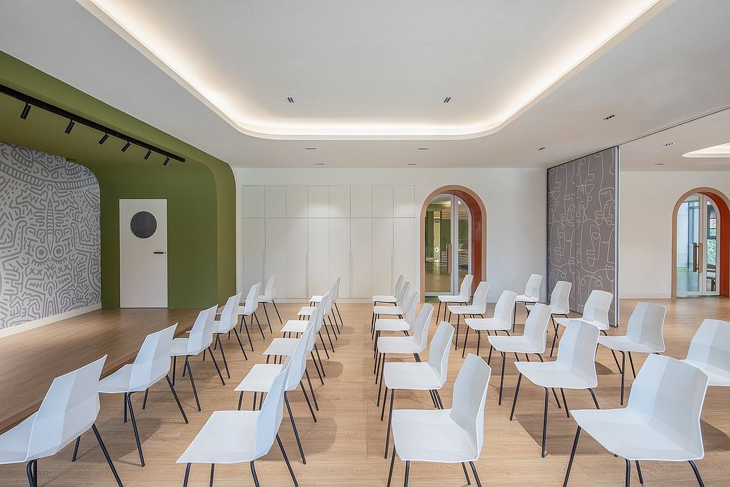 A modern, minimalist lecture hall with white chairs, wooden floors, and arched windows.