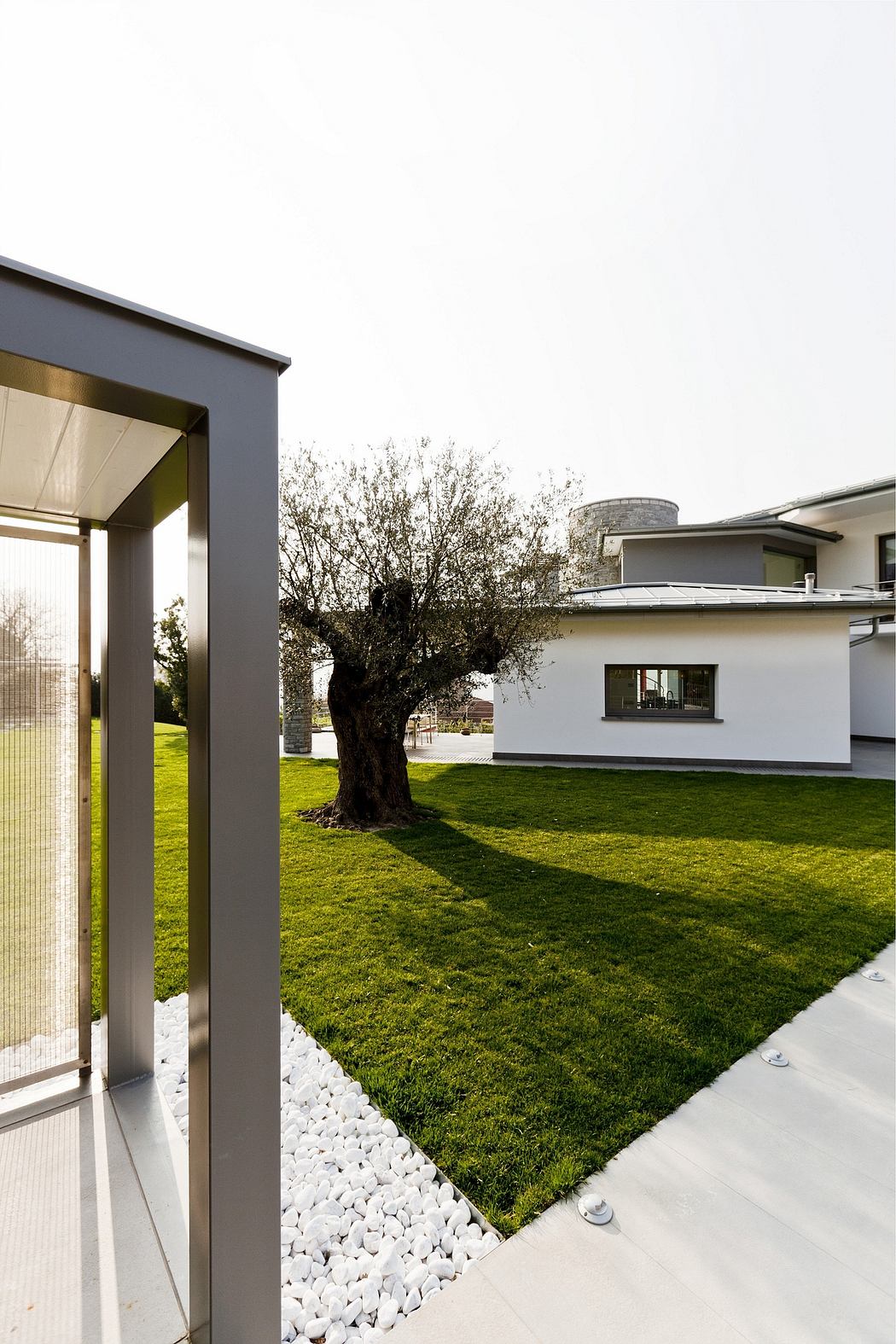 Sleek, modern architectural design with lush greenery, white stones, and clean lines.
