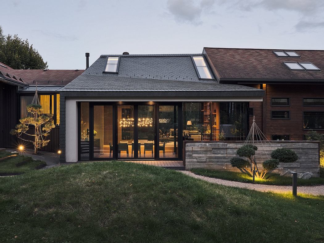 Luxurious contemporary home with stone facade, large windows, and warm lighting.