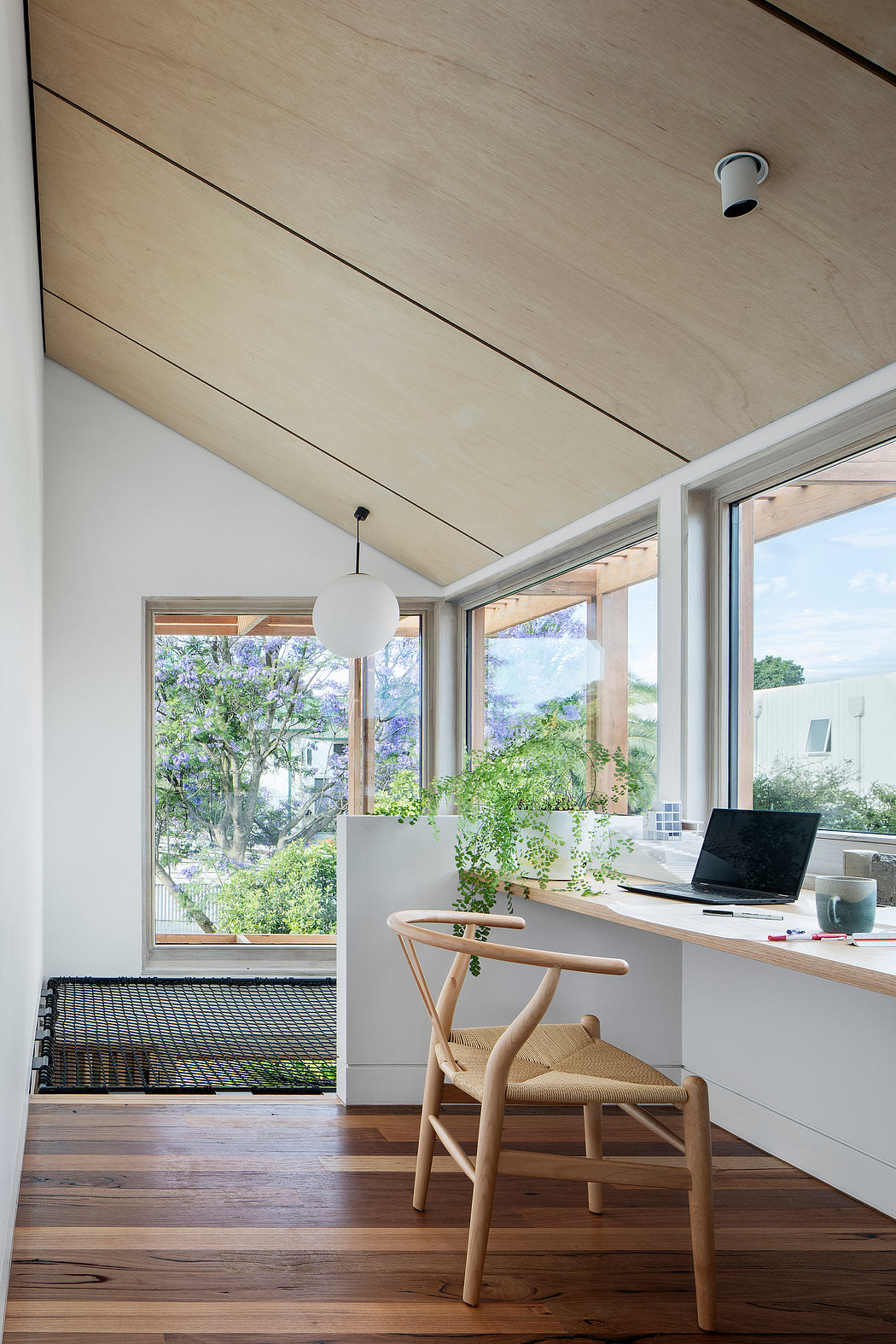 Cozy workspace with wooden accents, large windows, and lush greenery outside.