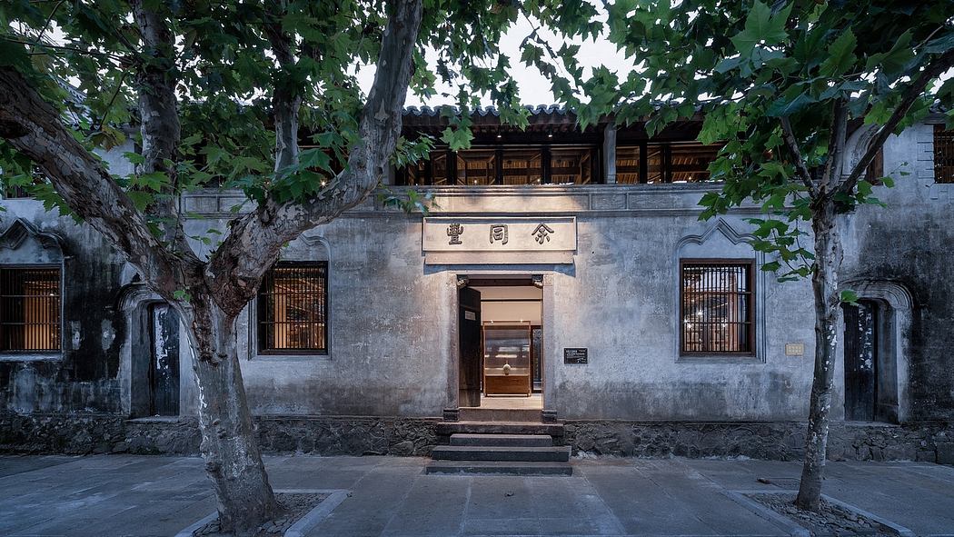 A traditional Chinese courtyard with a stone entrance, wooden beams, and lush foliage.
